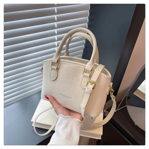 Close-up of cream leopard style bucket bag featuring embossed leather text and top handles
