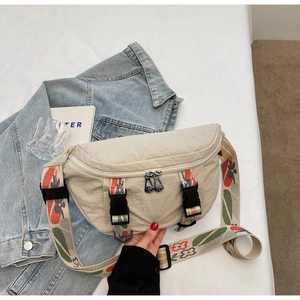 Detail of cream nylon chest bag featuring a vintage floral wide strap and plastic buckles