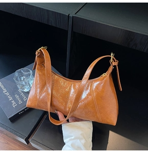 Détail d'un sac hobo plissé orange-brun avec finition brillante et détails dorés