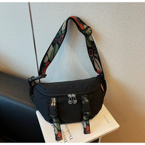 Close-up of black nylon chest bag featuring a vintage floral patterned wide woven strap