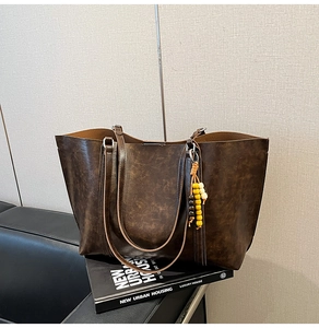 Close-up of vintage brown leather tote bag with decorative beads on a sofa