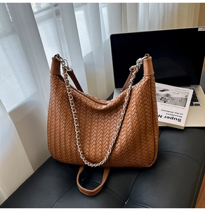 Macro detail of brown woven leather hobo bag with metallic chain strap and soft texture