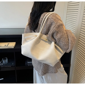 Detail of white woven texture on a large tote bag styled with a brown knit sweater