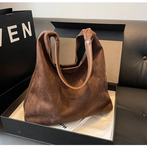 Detailed close-up of brown suede tote bag with leather handle and magnetic snap closure