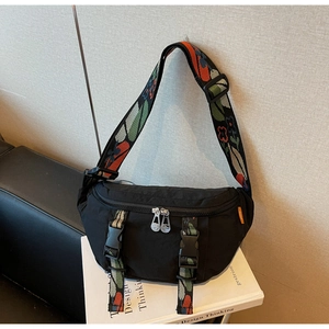 Detail of black nylon chest bag featuring functional buckles and colorful floral strap