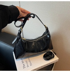 Détail du sac à main noir en cuir verni avec fermeture éclair et bandoulières doubles