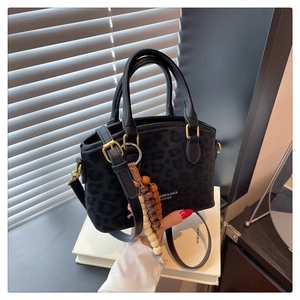 Close-up of leopard print bucket bag with wooden bead tassel and gold hardware