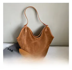 Detailed shot of dark brown suede tote bag with slim shoulder strap and smooth piping