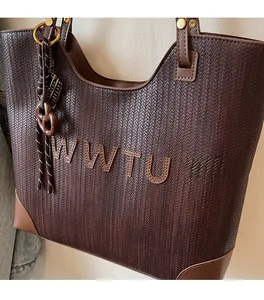Detail of dark brown woven tote bag with WWTU patch and elegant decorative charm