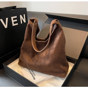 Detail of a brown suede hobo bag with leather handles in a luxury gift box setting