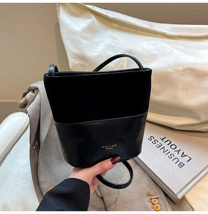 Detail of black bucket bag featuring mixed leather textures and golden logo lettering