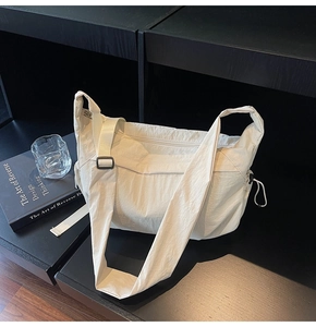 Dettaglio macro della borsa a mezzaluna in nylon crema con pieghe morbide e coulisse laterale