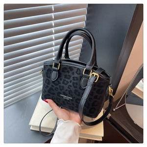 Detail of leopard print bucket bag with gold hardware and dual cylindrical handles