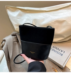 Detail of minimalist black patchwork bucket bag featuring suede and smooth leather textures