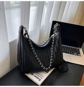 Close-up of black woven leather Hobo bag with silver chain strap on a desk setup