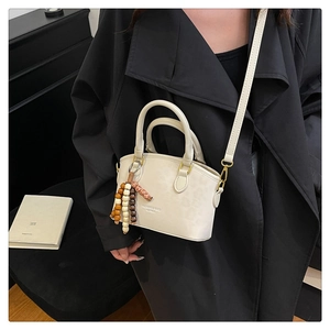 Detail of cream leopard print bucket bag with wooden bead charm and crossbody strap
