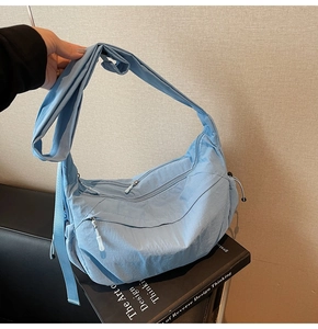 Dettaglio della borsa a tracolla in nylon blu con tasche con zip e tracolla larga