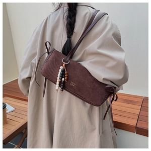 Detail of dark brown suede shoulder bag with ethnic beads and side leather straps