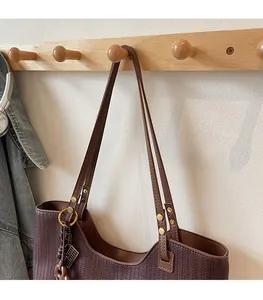 Close-up of deep coffee woven tote bag with gold hardware on a wooden rack