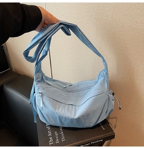 Dettaglio della borsa a mezzaluna in nylon azzurro con tracolla regolabile e zip esterna