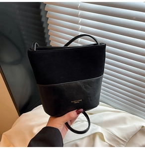 Detail of black bucket bag featuring suede and leather texture with gold logo