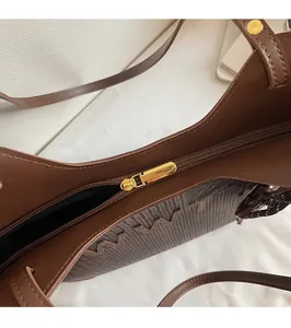 Detailed view of the smooth gold metal zipper and stitching on the brown tote bag