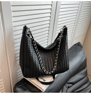 Detailed close-up of the black woven leather texture and silver chain on the shoulder bag