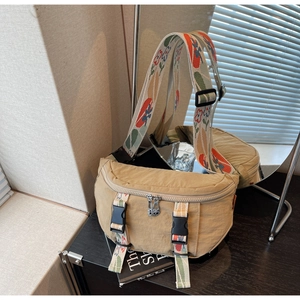 Detail of khaki canvas sling bag featuring jacquard floral strap and secure plastic buckles