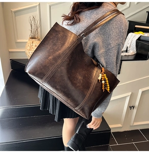 Detail of vintage brown leather tote bag with vertical stitching and beaded tassel charm