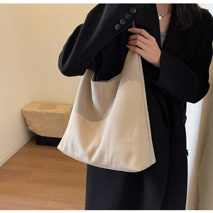 Detail of minimalist beige suede tote bag draped on model's shoulder in office attire