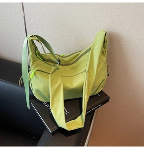 Dettaglio della borsa a tracolla in nylon verde con tasche a zip e tiretti verde fluorescente