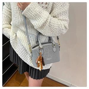 Close-up of gray leopard print bucket bag with decorative wooden beads and slim straps