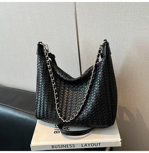 Close-up of woven black hobo bag detail with silver chain and leather texture