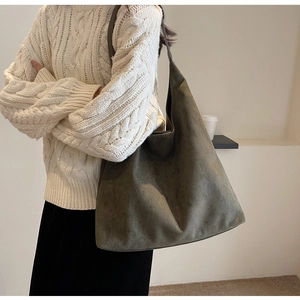 Detailed view of olive suede tote bag styled with a warm knit sweater for a minimalist look