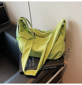 Dettaglio borsa a tracolla in nylon verde avocado con tracolla regolabile su panca