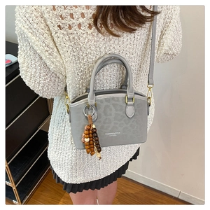 Detail of grey leopard print bucket bag with ethnic beaded tassel and gold hardware