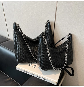 Close-up of black woven leather texture and silver chain detail on a large hobo bag
