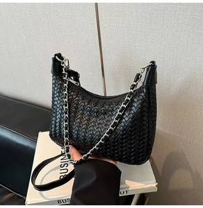Close-up of black woven leather texture and elegant silver chain strap on hobo bag