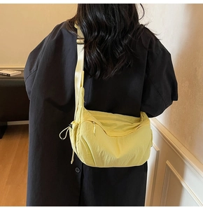 Modella che indossa una borsa a tracolla in nylon giallo acceso su un cappotto nero