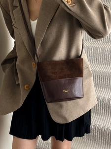 Retro brown bucket bag in textured patchwork leather, worn with a stylish khaki suit