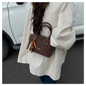 Detailed view of leopard print crossbody bag with wooden bead charm and thin strap