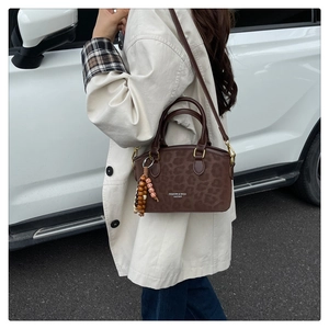 Detail of coffee leopard print crossbody bag with fashion text and beaded keychain