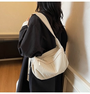 Dettaglio borsa a sacchetto in tela beige con lacci decorativi e ampia tracolla regolabile