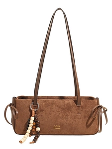 Brown faux suede shoulder bag with beaded charm and gold logo on white background