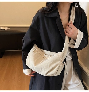 Dettaglio della borsa a tracolla in nylon crema con coulisse e chiusura a zip