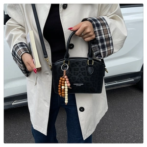 Detail of leopard print bucket bag with wooden bead tassel and metal ring buckle