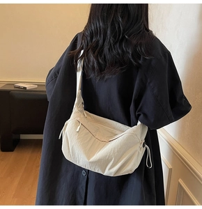 Vista dettagliata della borsa a tracolla in nylon crema con coulisse e tasca con zip