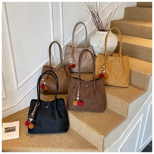 Detail of five large matte suede tote bags in warm earth tones on a beige staircase