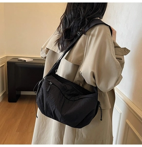 Dettaglio di una grande borsa a tracolla nera in nylon con design moderno e cinturino largo
