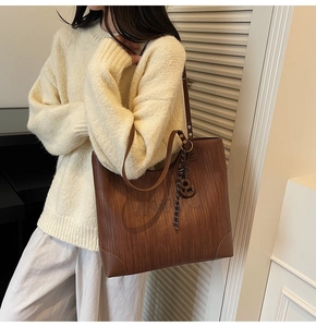 Detail of a dark brown tote bag with woven texture and a large embossed W letter
